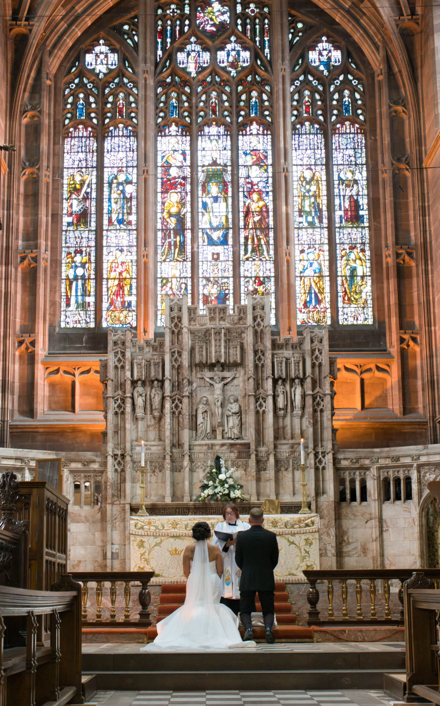 A bride and groom Neal  in front of the beautiful high altar atSt George's Church London Road, Stockport
